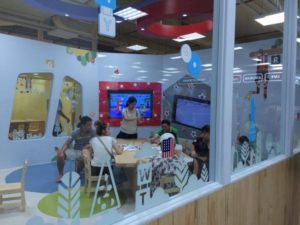 Phòng hoạt động kính tại Apple Kids Clup, nhóm phụ huynh và trẻ ngồi quanh bàn, nhân viên hướng dẫn