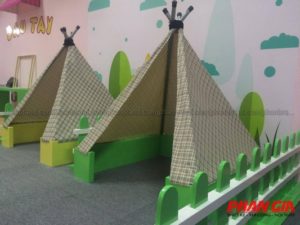 Dãy lều tipi vải kẻ trong khu vui chơi trẻ em trong nhà, kèm hàng rào xanh và tường trang trí 'Dâu Tây'
