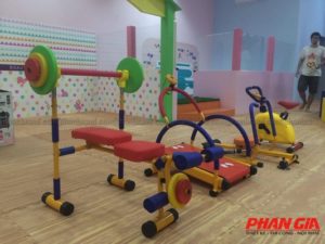 Khu tập gym trẻ em trong nhà với bộ dụng cụ thể thao mini nhiều màu, ghế tập và xe đạp tập