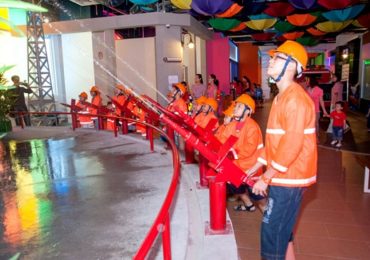 Trẻ em mặc áo bảo hộ bắn vòi phun chữa cháy trong khu vui chơi hướng nghiệp