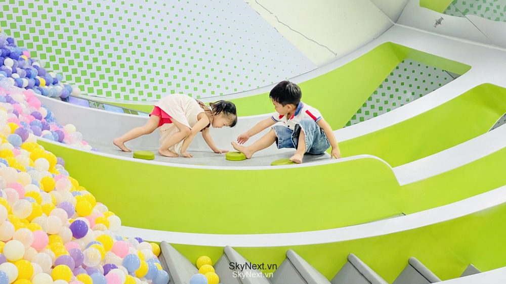 Hai trẻ em đang chơi trên những đường trượt xanh cạnh hố bóng